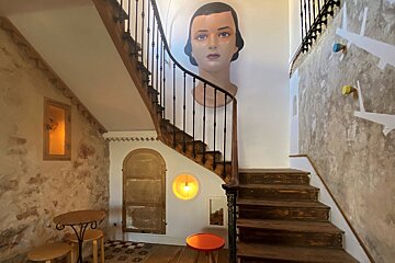 A staircase with a painting of a woman 's head on the wall
