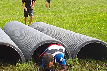 a man crawling through a tunnel on the grass