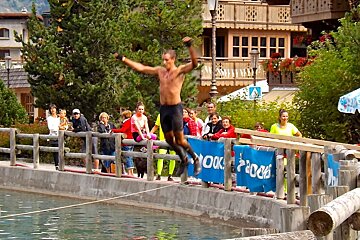 a man jumping off a plank into the lake