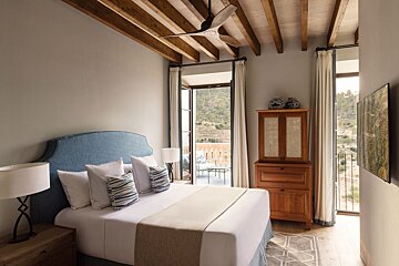 A bedroom with a large bed and a ceiling fan