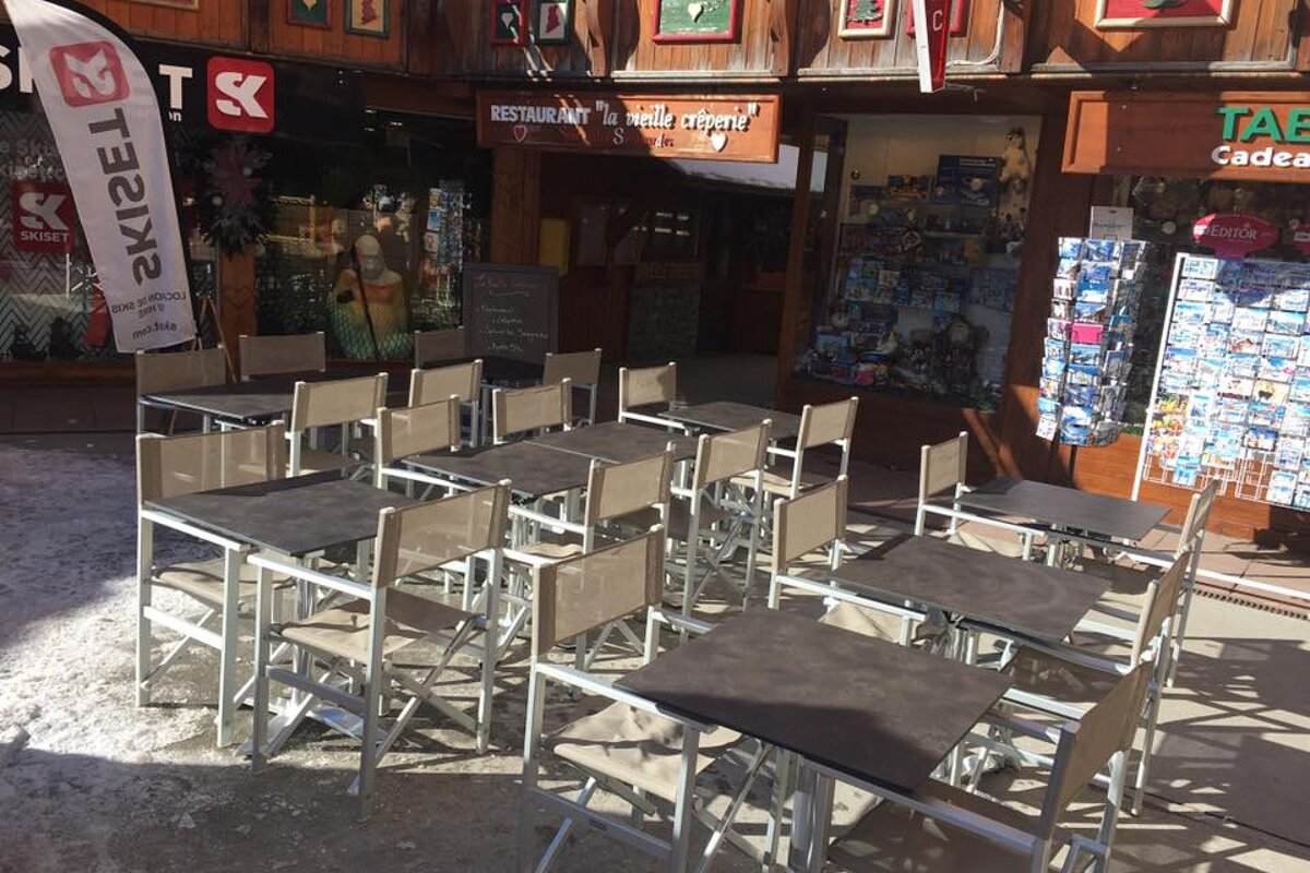 Tables and chairs outside a restaurant with a flag that says ta2el