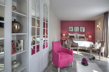 A bedroom with a bed and a pink chair