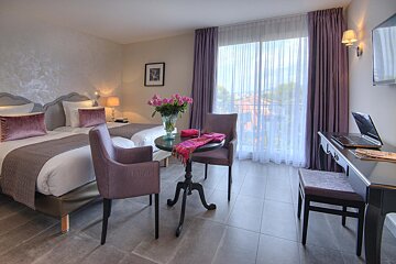 A hotel room with two beds and a table with a laptop on it