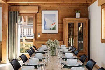 A dining room table with a picture of a ski lift on the wall above it