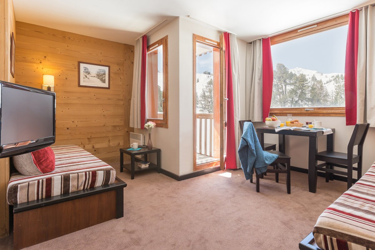 A hotel room with a table and chairs and a television
