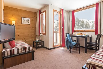A hotel room with a table and chairs and a television
