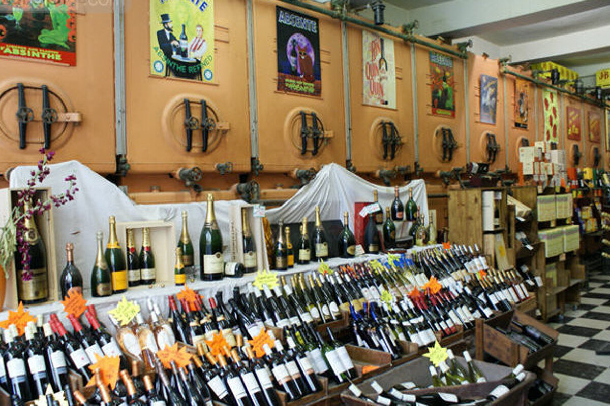 Many bottles of wine are displayed in a store with a sign that says absinthe
