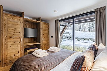 A bedroom with a large bed and a flat screen tv