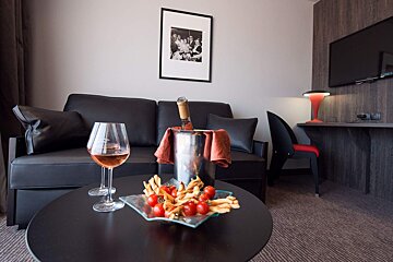 A bottle of champagne sits on a table next to a bowl of food