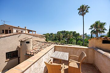 A balcony with a table and chairs and a palm tree in the background