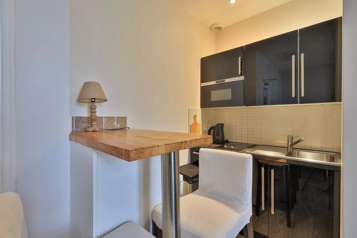 A small kitchen with black cabinets and a wooden table
