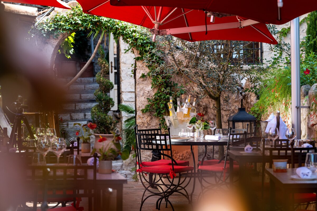 A restaurant with tables and chairs under red umbrellas