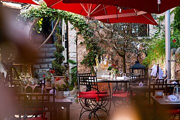 A restaurant with tables and chairs under red umbrellas
