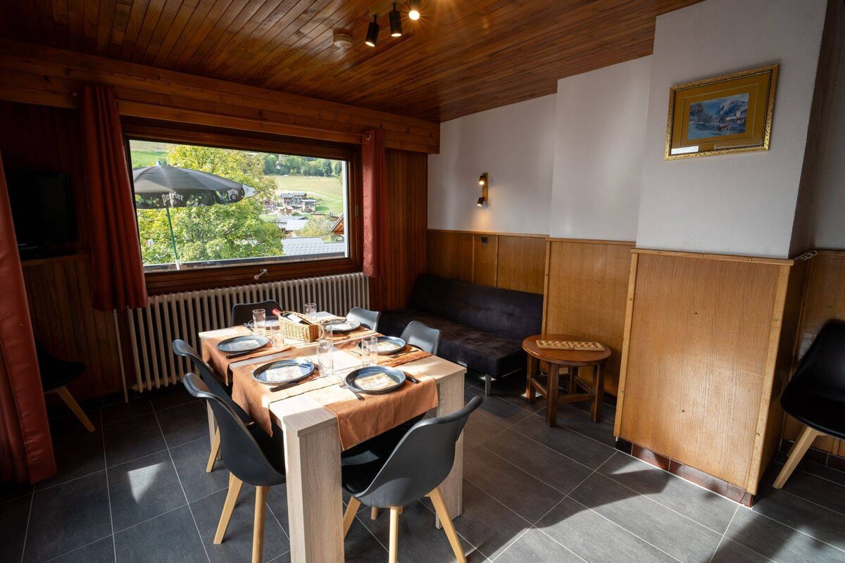 A dining room with a table and chairs and a painting on the wall