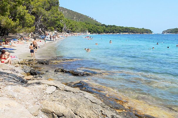 people on the beach & rocks & in the blue water