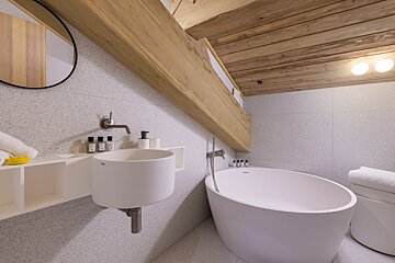 A bathroom with a sink and a bathtub with bottles of lotion on the shelf