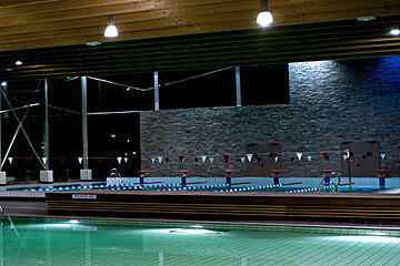 A large indoor swimming pool is lit up at night