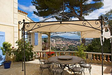 A table and chairs under a canopy overlooking a city