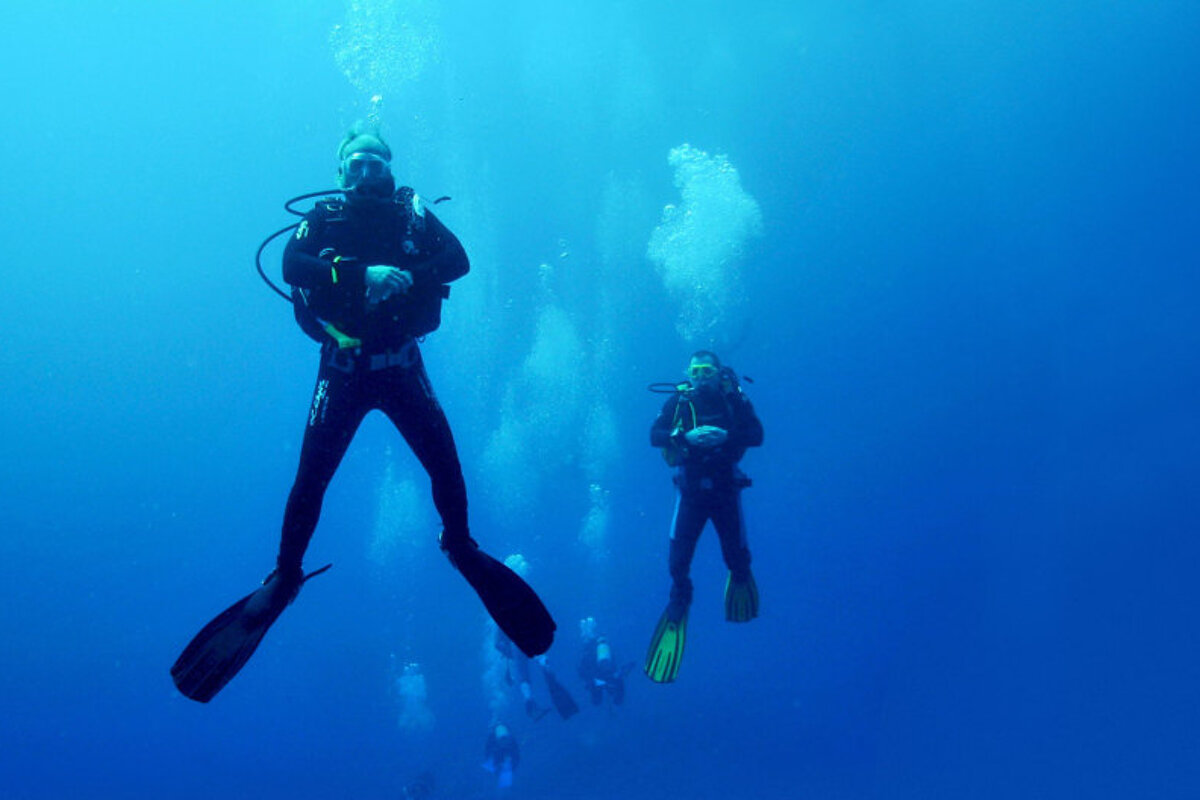 Two scuba divers are swimming in a blue ocean