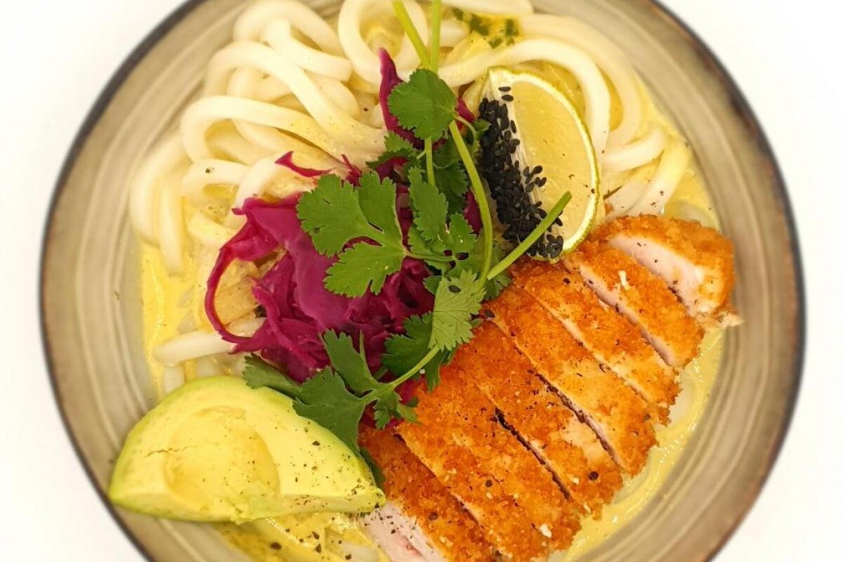 A bowl of food with chicken avocado and cabbage