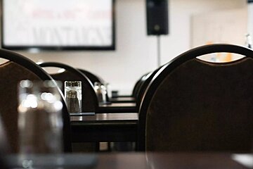 A row of tables and chairs with a projection screen behind them that says summit