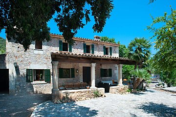 A stone house with green shutters on the windows