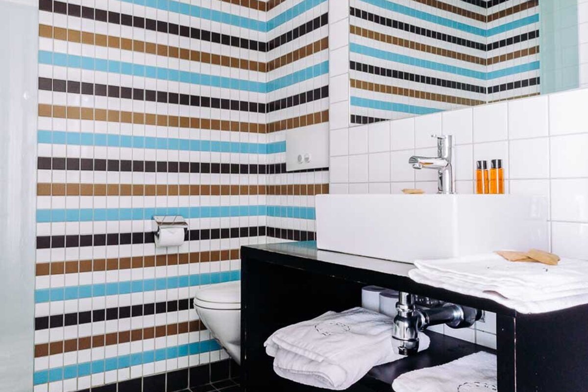A bathroom with striped tiles and a toilet