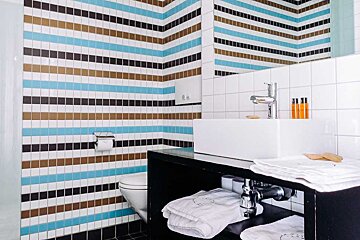A bathroom with striped tiles and a toilet