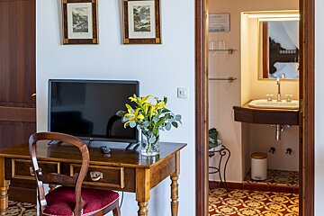 A desk with a flat screen tv and a vase of flowers on it