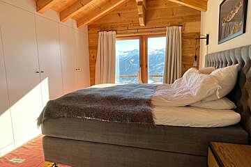 A bedroom with a bed and a window with mountains in the background