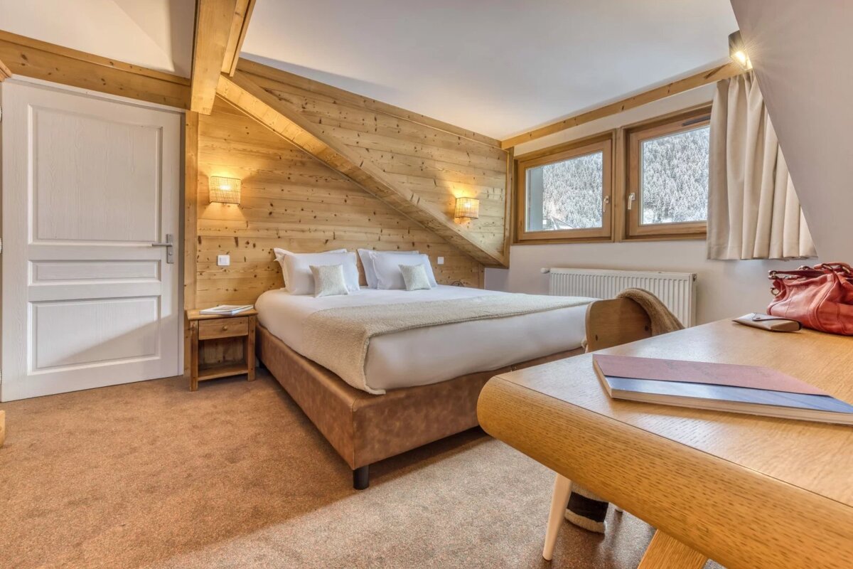 A bedroom with a bed and a desk with a book on it
