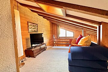 A living room with a blue couch and a flat screen tv