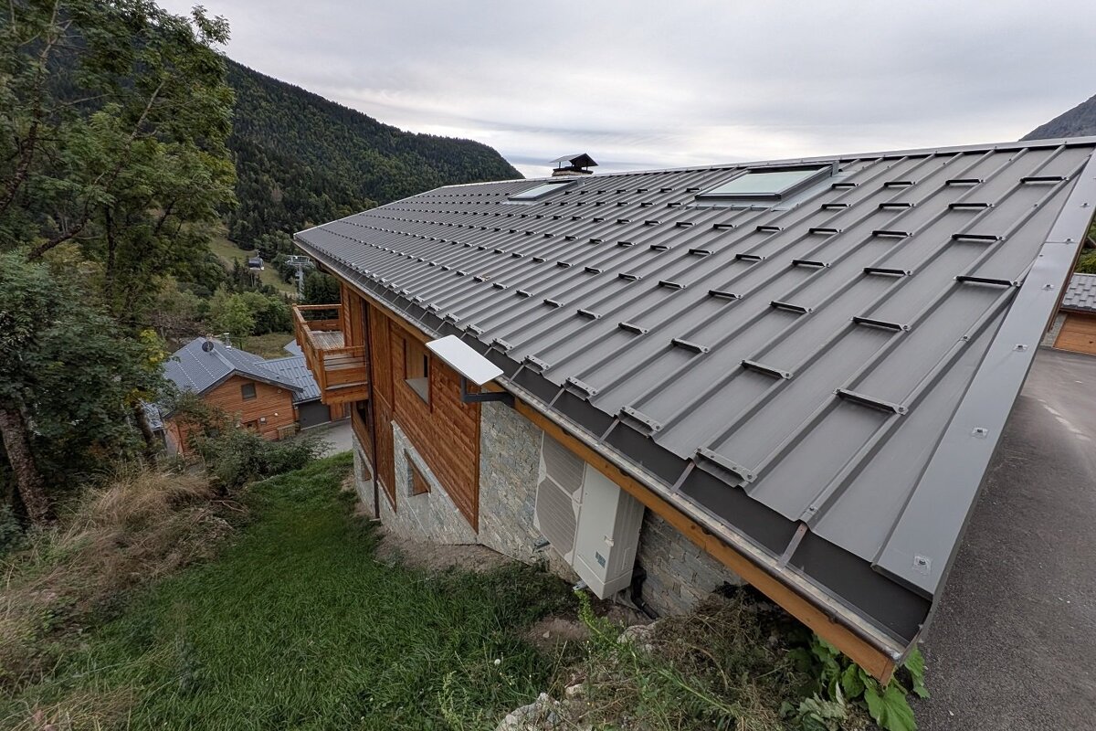 A house with a gray metal roof and a skylight
