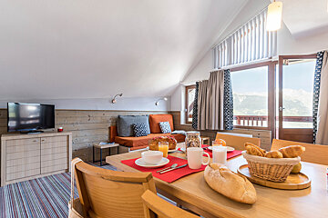 A dining room table with a basket of bread on it
