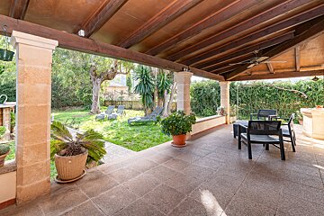 A patio with chairs and a table under a wooden roof