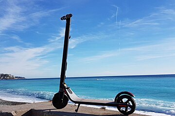 A scooter is parked on the beach with the ocean in the background