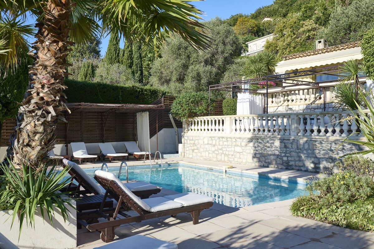 A large swimming pool is surrounded by chairs and palm trees