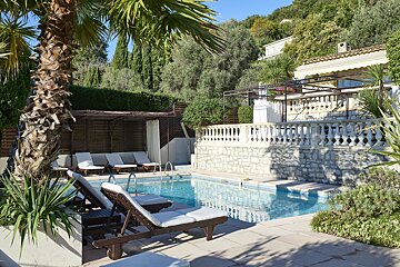 A large swimming pool is surrounded by chairs and palm trees