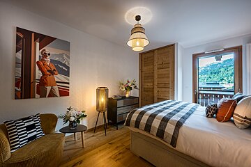 A bedroom with a large bed and a painting on the wall