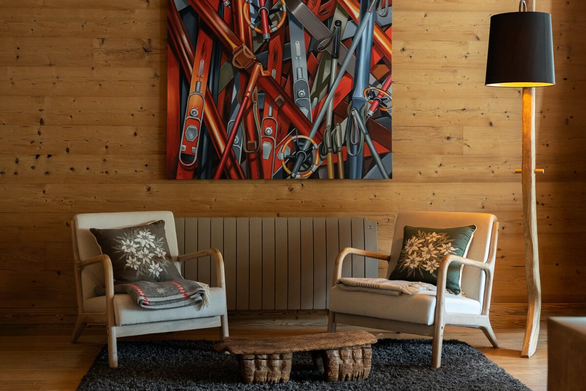 Two chairs in a living room with a painting on the wall above them