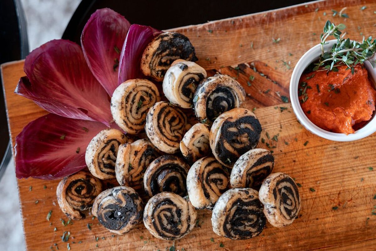 A wooden cutting board with a bunch of food and a bowl of sauce