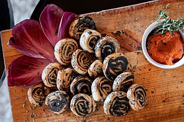 A wooden cutting board with a bunch of food and a bowl of sauce