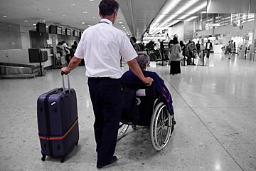 a man pushing a lady in a wheelchair in the airport