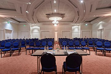 A conference room with rows of blue chairs and tables