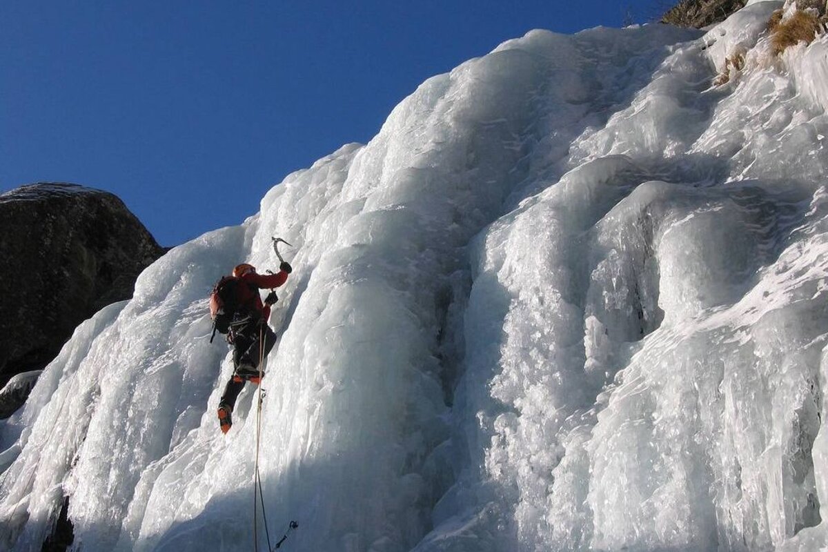 a man climbing an icy waterfall