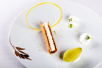 A white plate with a leaf on it and a dessert on it