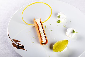 A white plate with a leaf on it and a dessert on it
