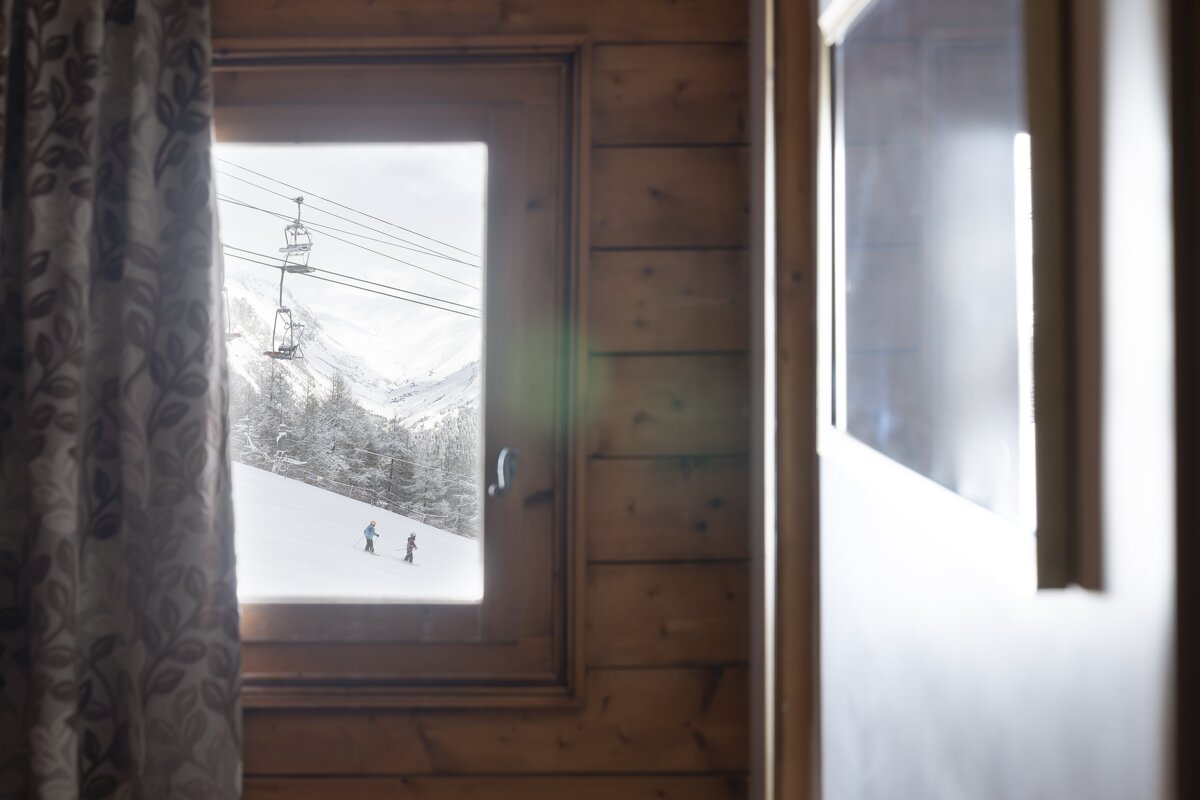 A ski lift is visible through the window of a cabin