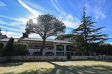 A large house with a tennis court in front of it