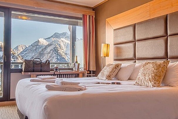 A hotel room with a large bed and a view of mountains